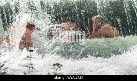 Munich, Allemagne. 24 juillet, 2019. Les enfants jouent à une petite cascade dans le jardin anglais de l'Eisbach. Crédit : Peter Kneffel/dpa/Alamy Live News Banque D'Images