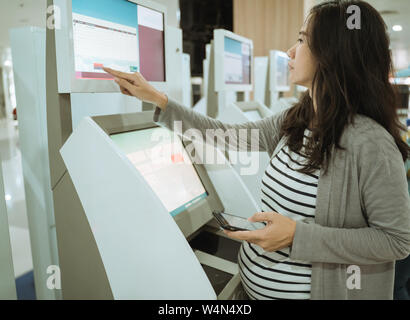 Les femmes asiatiques confirment le poids de l'ordinateur en utilisant des objets transportés Banque D'Images