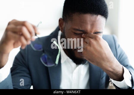 Fatigué african businessman en tenant ses lunettes Banque D'Images