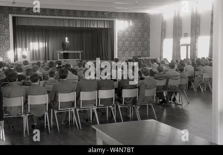 Années 1950, historiques, directeur en robe, sur une scène dans la salle d'école s'adressant à ses élèves, England, UK. Banque D'Images