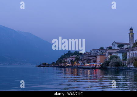 Une vue sur le lac de Garde au crépuscule avec la ville sur la droite, et les montagnes sur la gauche. Banque D'Images