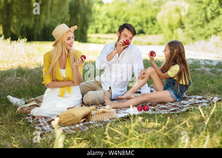 Happy Family having picnic et manger des pommes dans park Banque D'Images