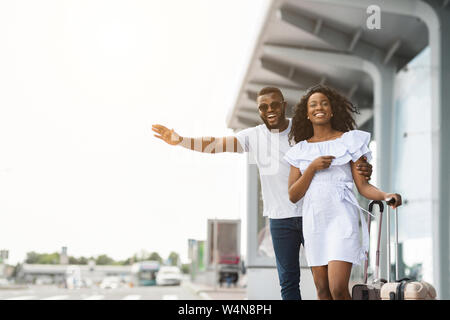 African American man and woman tente de prendre des taxi, arrivant à l'aéroport Banque D'Images