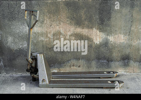 Transpalette manuel gris, avec du ciment wall background Banque D'Images