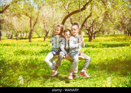 Trois petits enfants jouer sur les balançoires dans un parc sur une chaude journée d'été Banque D'Images
