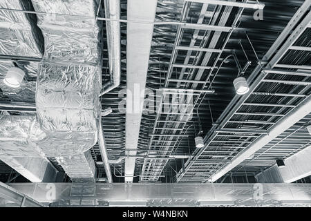 Le tuyau d'air de ventilation de l'air au plafond et les câbles de données manged dans un téléphérique sur le toit du bureau Banque D'Images