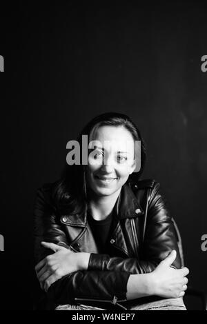 Studio portrait d'une belle jeune femme dans une veste en cuir noire contre un fond uni Banque D'Images