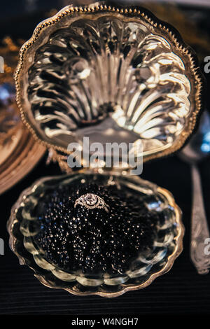Libre de bague de fiançailles avec un énorme diamant dans un bol avec du caviar noir, décor élégant pour une cérémonie de mariage, selective focus Banque D'Images