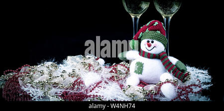 Fun toy snowman et deux verres de champagne sur un fond noir.photo with copy space Banque D'Images