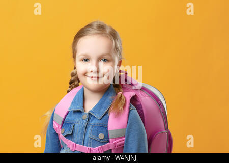 Portrait d'une petite fille écolière avec un sac à dos sur un fond jaune. Retour à l'école. Le concept de l'éducation. Copier l'espace. Banque D'Images