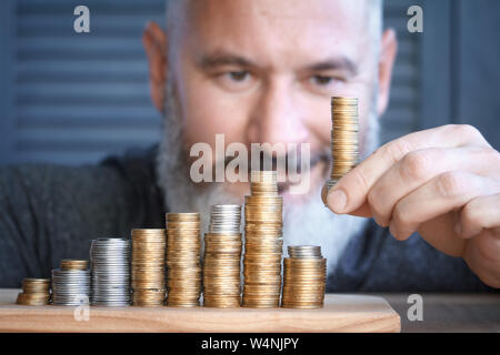 L'homme libre de colonnes recueille des pièces multi-couleur de l'augmentation de la hauteur, le concept d'accumulation et d'économiser de l'argent, selective focus Banque D'Images