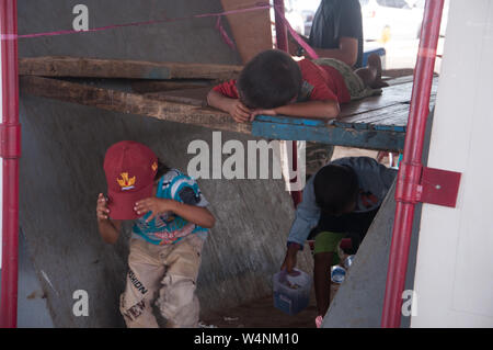 Les enfants des rues à pied sous une plate-forme de bois tandis qu'un garçon slleping sur elle. Banque D'Images