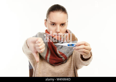 Portrait d'une femme malade en beige pull et une écharpe à très malade est titulaire d'un thermomètre. Banque D'Images