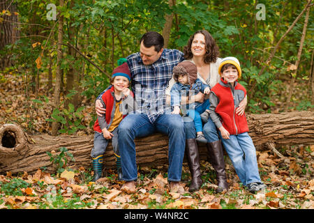 Portrait d'une famille assis ensemble dans un parc boisé Banque D'Images