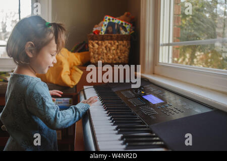 Portrait d'un mignon petit enfant à jouer du piano devant une fenêtre