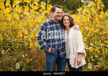 Un sourire heureux couple stand bras dessus, bras dessous dans une prairie d'or Banque D'Images