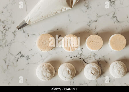 Macaron cookie coquillages organisé avec poche à douille pleine de buttercream Banque D'Images