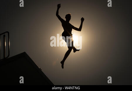 Bielefeld, Allemagne. 24 juillet, 2019. Un nageur saute d'une tour de 10 mètres dans une piscine extérieure contre le soleil. Credit : Friso Gentsch/dpa/Alamy Live News Banque D'Images