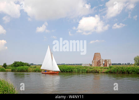 Un yacht à voile plein approche de l'abbaye St Benet ruines sur la rivière Bure sur les Norfolk Broads à South Walsham, Norfolk, Angleterre, Royaume-Uni, Europe. Banque D'Images