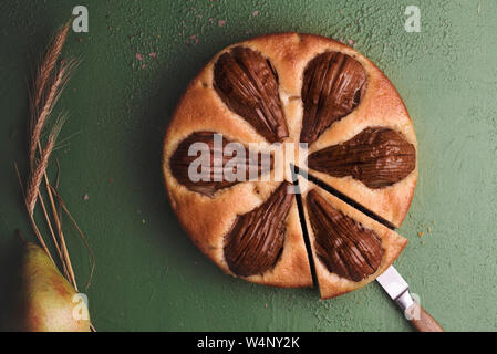 Gâteau fait maison avec des poires entières sur un tableau vert. Seule tranche de poire tarte. Dessert d'automne Banque D'Images