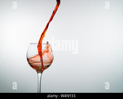 Vin rouge remplit un verre de vin vide sur un fond blanc Banque D'Images