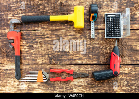 Vieux outils à main, pinces, marteau, ruban de mesure, clé à molette, tournevis électrique avec un ensemble de bits, un ensemble de clés hexagonales sont situés sur l'ancien woo Banque D'Images