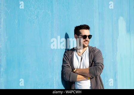 Portrait de jeune homme barbu avec des lunettes leaning against wall Banque D'Images