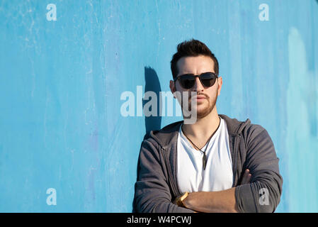 Portrait de jeune homme barbu avec des lunettes leaning against wall Banque D'Images