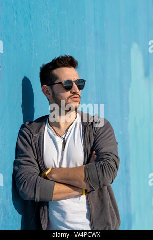 Portrait de jeune homme barbu avec des lunettes leaning against wall Banque D'Images