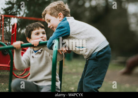 Deux frères jouant sur merry go round Banque D'Images