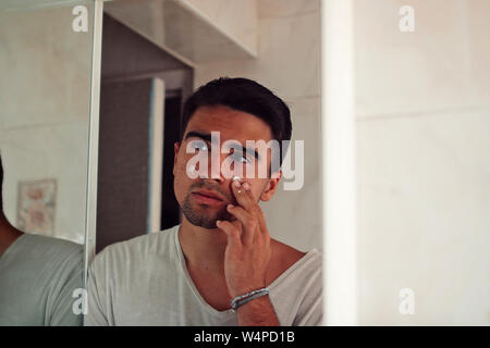 L'homme vêtu de blanc crème à mettre sur son visage. Banque D'Images