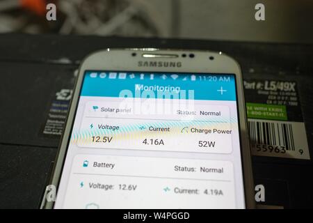 Close-up of Samsung smartphone avec application de surveillance des panneaux solaires solar entreprise Renogy, placé au-dessus d'un banc de batteries et d'être utilisés pour surveiller les performances d'un résidentiel solaire hors réseau dans la baie de San Ramon, Californie, le 10 septembre 2018. () Banque D'Images
