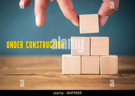 Main est vide d'empilage de cubes et le message 'en construction' sur fond de bois Banque D'Images