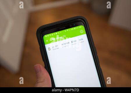 Close-up de main d'un homme tenant un portable afficher le Presse-citron vert app, montrant l'état de la charge d'un scooter électrique Lime dockless, San Ramon, Californie ; économie concert chaux emploie des entrepreneurs indépendants, connu sous le nom de centrifugeuses, de facturer et de déployer son dockless scooters, 18 octobre 2018. () Banque D'Images