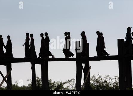 Silhouette de jeunes novices bouddhistes sur le U-Pont de la jambe au lac Taungthaman, Myanmar Banque D'Images