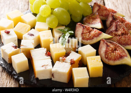 Ensemble d'apéritifs de fromage, raisins et figues sur une liste de sélection sur la table. L'horizontale Banque D'Images