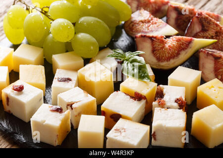 Délicieux apéritif de divers fromages, raisins et figues close-up sur la table horizontale. Banque D'Images
