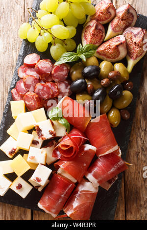 Snack-méditerranéenne de plateau de fromages, jambon prosciutto, raisins, figues, olives et saucissons de près. Haut Vertical Vue de dessus Banque D'Images
