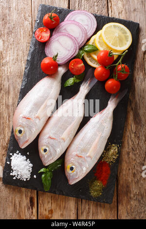 La mer de poissons ingrédients avec bram close-up sur une liste de sélection sur la table. Haut Vertical Vue de dessus Banque D'Images