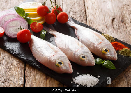 Matières premières fraîches dorado ou la brème de mer Poisson aux épices, tomates, oignons et citron libre sur une liste de sélection sur la table horizontale. Banque D'Images