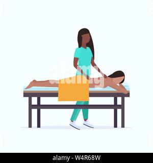 Jeune fille ayant massage dos african american masseuse-thérapeute en massage corps uniforme patient woman lying on bed traitements spa salon Illustration de Vecteur