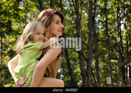 Le bonheur de la famille. Jeune fille à cheval sa maman est de retour, sur la nature dans le parc. Maman Concept fille. Banque D'Images