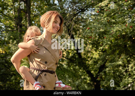 Le bonheur de la famille. Jeune fille à cheval sa maman est de retour, sur la nature dans le parc. Maman Concept fille. Banque D'Images