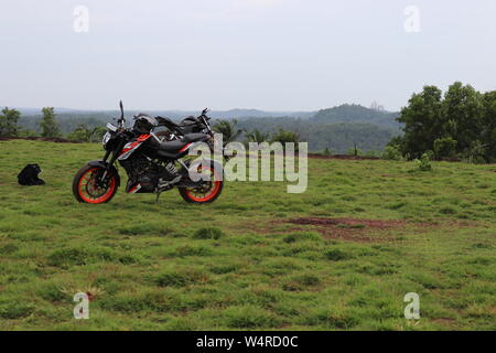 Une orange sports moto reposant sur une colline verte avec de belles montagnes en arrière-plan Banque D'Images