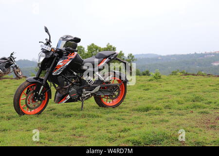 Une orange sports moto reposant sur une colline verte avec de belles montagnes en arrière-plan Banque D'Images