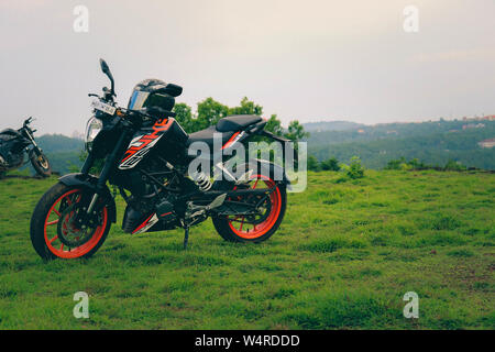 Une orange sports moto reposant sur une colline verte avec de belles montagnes en arrière-plan Banque D'Images