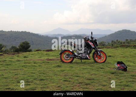 Une orange sports moto reposant sur une colline verte avec de belles montagnes en arrière-plan Banque D'Images