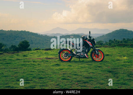 Une orange sports moto reposant sur une colline verte avec de belles montagnes en arrière-plan Banque D'Images