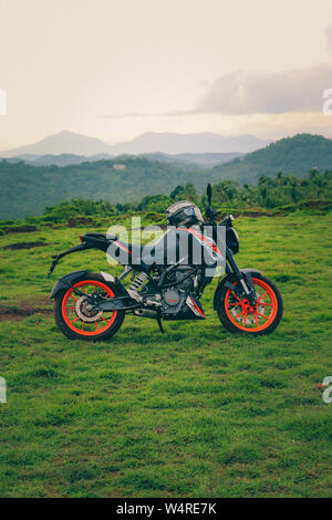 Une orange sports moto reposant sur une colline verte avec de belles montagnes en arrière-plan Banque D'Images