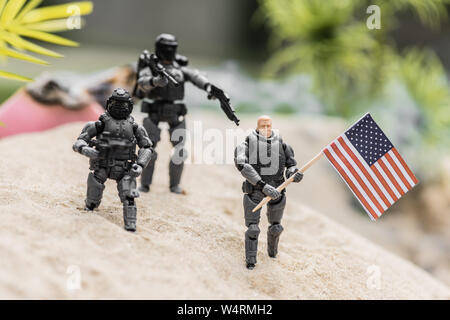 Focus sélectif de petits soldats en plastique avec des armes visant à toy man avec le drapeau américain sur la colline de sable Banque D'Images